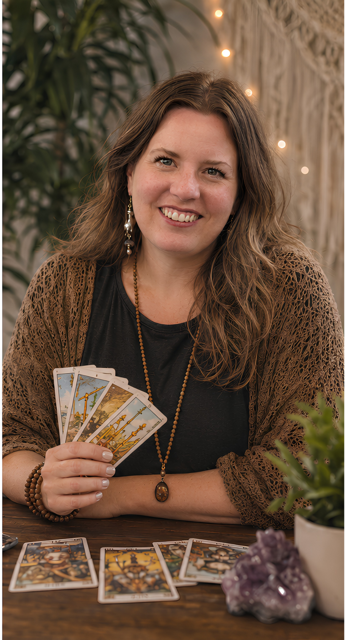 Katie holding a fanned tarot deck above a cloth covered table